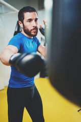 Concept of a healthy lifestyle.Young athlete fighter practicing kicks with punching bag.Kick boxer boxing as exercise for the fight.Boxer man hits punching bag.Vertical.