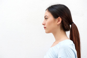 Side portrait of casual young woman standing alone