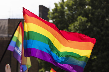Gay rainbow flag being waved at an LGBT gay pride march in London