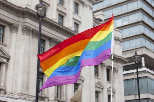 Gay rainbow flag being waved at an LGBT gay pride march in London
