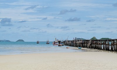 Fototapeta na wymiar Sea and white sand beach under the blue sky and the old bridge for boat fishing.