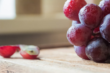 Blue grapes lie on a wooden background. Grapes macro. Grapes with droplets of water. Grapes in a cut. Grapes and wine corks. Blue and green grapes