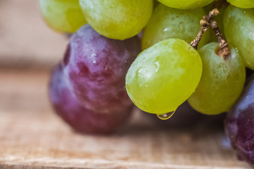 Blue grapes lie on a wooden background. Grapes macro. Grapes with droplets of water. Grapes in a cut. Grapes and wine corks. Blue and green grapes