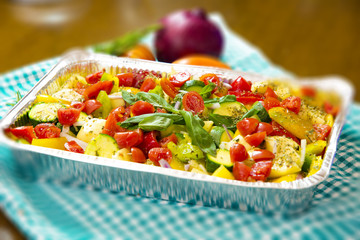 Baked potatoes with zucchini, capers, olives, peppers, cherry tomatoes, basil, oregano. Cooked in aluminum pot.