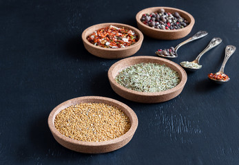 Spices in a small plates on black background Variety of spices Copy space Spice and herbs Spoons with spices