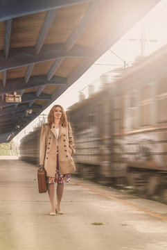Woman with a suitcase, waiting for the train and sets of railway station. Young woman goes stripe sets and loneliness