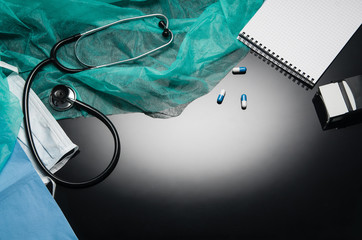 Top view of modern, sterile doctors office desk. Medical accessories on a black reflective table background with copy space around products. Photo taken from above.