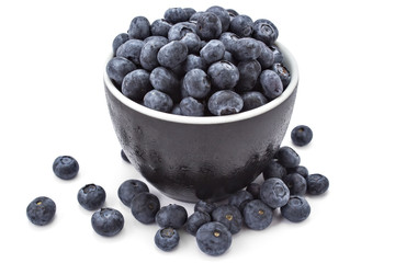 Fresh ripe organic blueberries in a frozen black bowl on a white background