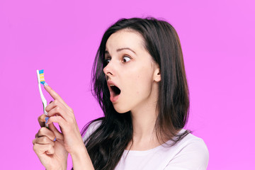 Beautiful young woman on a blue background holds a toothbrush