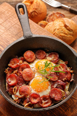 Cooked egg and sausages on frying pan