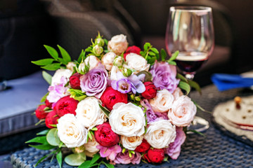 A beautiful bouquet of flowers and a glass of wine. Romantic date. The concept of marriage and love.