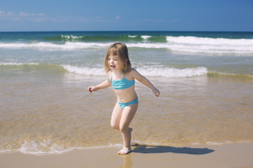 little girl run play with waves on the beach