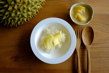 Sticky rice with durian and coconut milk separate ready to eat, set on the wooden table with wooden spoon
