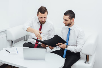 Fototapeta premium Two business partners working with documents, laptop and phone at office