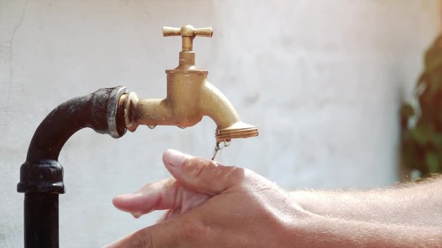 super slow motion shot of exterior tap water dripping and splash on a hot summer day