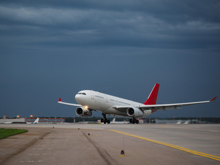 Airplane on the runway in the background of a rainy sky