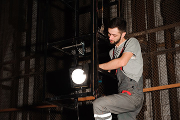 Fototapeta na wymiar The lighting engineer adjusts the lights on stage behind the scenes