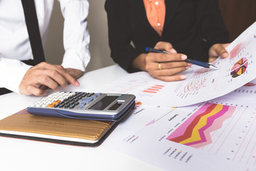 Calculator on notebook with background motion two businessman discussing the charts and graphs...
