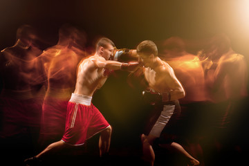The two male boxers boxing in a dark studio