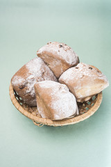 Homemade muffins with raisins and powdered sugar in a wicker basket against a light mint color, vertical frame