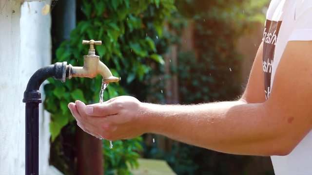 super slow motion shot of faucet, young man drinking fresh water dripping and splash on a hot summer day