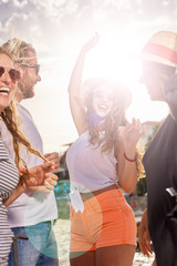 Group of people dancing, chatting and having a good time at beach party - obrazy, fototapety, plakaty