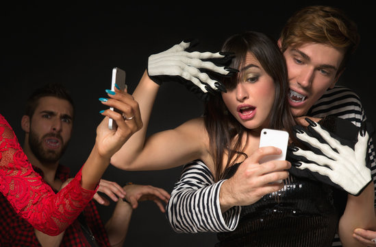 Cool friends in costume dancing at Halloween Party and taking selfies