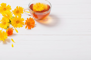 Calendula (Marigold) herbal tea  on white wooden table