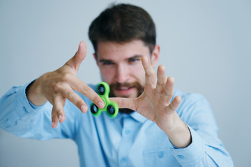 A young guy with a beard on a light background holds a spinner