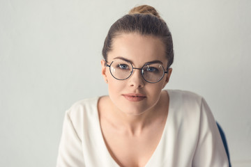 Fototapeta premium attractive stylish businesswoman in eyeglasses sitting in modern office