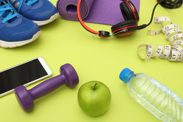 Athlete's set  dumbbells and bottle of water, Yoga mat, sport shoes,  on yellow  background. Concept healthy lifestyle, sport and diet. Sport equipment. Copy space