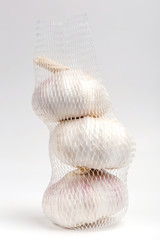 Row white garlic bulbs in net package with white background, general and useful seasoning for tasty foods. © mrcmos