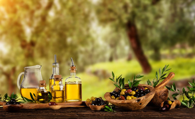 Panele Szklane  Świeżo zebrane oliwki jagody w drewnianych miskach i tłoczony olej w szklanych butelkach