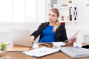Pregnant business lady at work reading papers