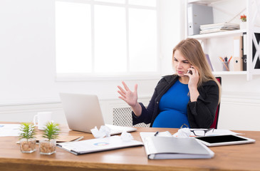 Obraz na płótnie Canvas Pregnant business lady at work talking on phone