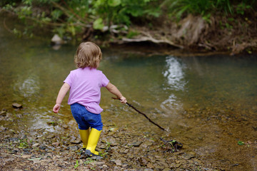 The little cute girl walks at the river in the fresh air