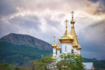 Fototapeta na wymiar Золотые купола русской православной церкви на фоне гор