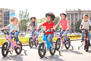 Cute little children riding bicycles outdoors on sunny day