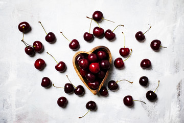 Fresh sweet cherries in wooden bowl in the shape of  heart, top view