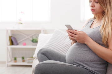 Young pregnant woman using smartphone copy space