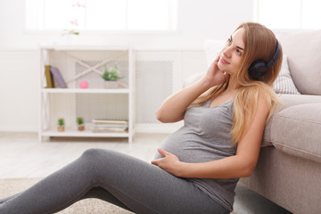 Pregnant woman listening music in headphones