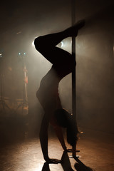Fototapeta na wymiar Young sexy woman exercise pole dance on a dark background