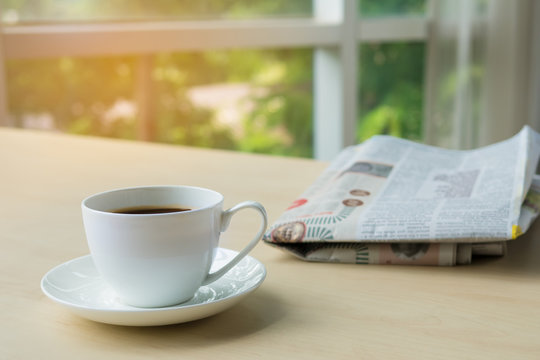 Cup of coffee with newspaper on the table in the morning , warm tone background