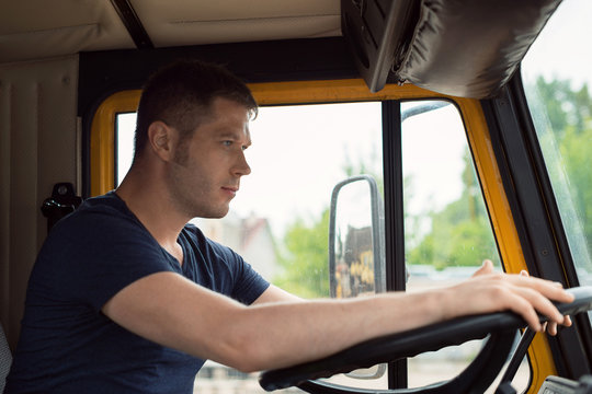 Male trucker in cabin of his yellow truck.