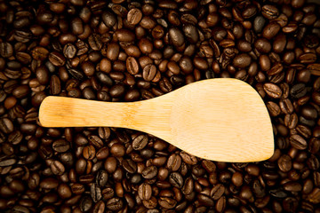 Fototapeta premium Wood spoon rests on coffee beans.