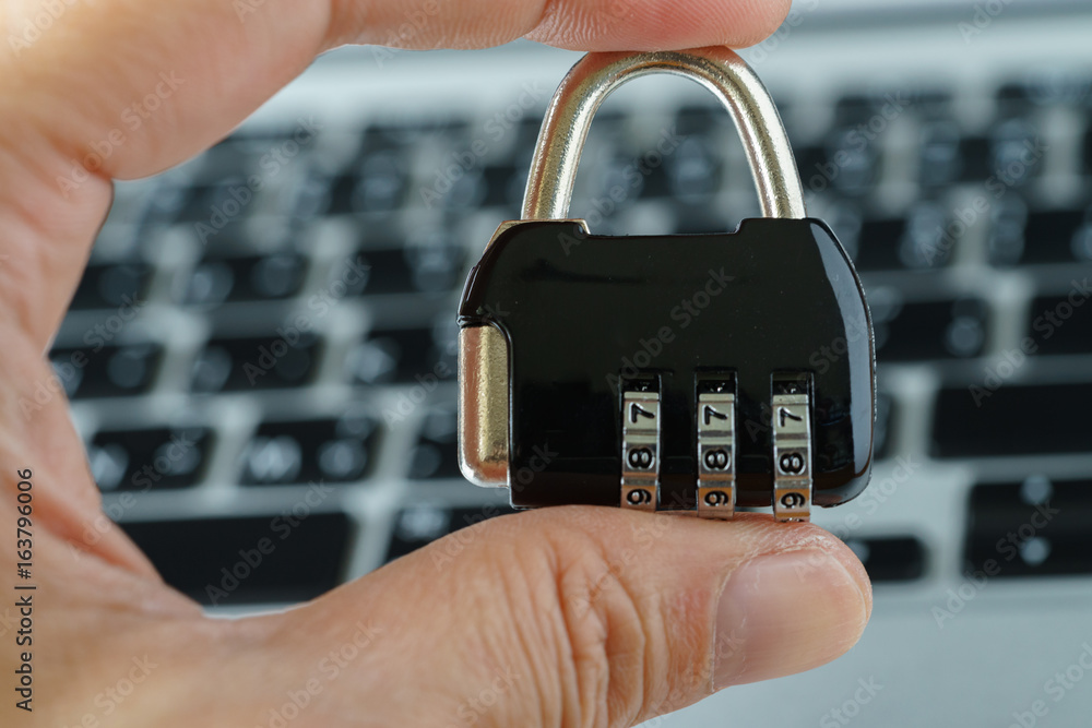 Aufkleber computer security concept, with hand holding combination lock pad with the background of computer ke