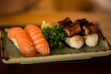 Sushi Salmon and Sushi eel is placed in a dish on a wooden table.