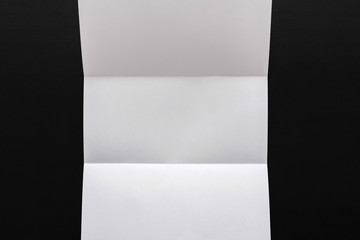 White folded sheet of paper on black background