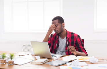 Tired black businessman in office, work with laptop