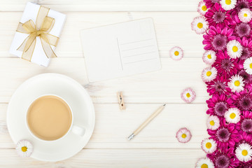 garden flowers, coffee cup and empty postcard on white wooden rustic table background. vintage card, flat lay, top view. breakfast on Mothers day or Womens day